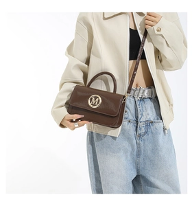 Brown patent leather mini bag with golden M logo styled on a beige jacket outfit