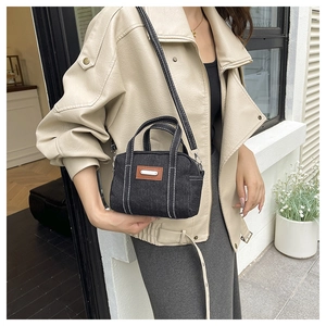 Detail of black denim square bag with contrast stitching and adjustable crossbody strap