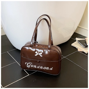 Detail of dark brown glossy shoulder bag with silver bow buckle and embroidery