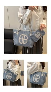 Detail of blue denim tote bag with circular logo cutout and matching internal zipper pouch