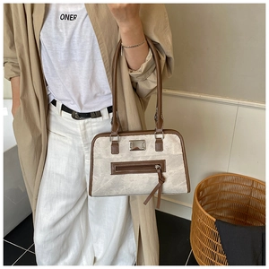 Détail du sac cabas rétro en tissu beige avec bordure en cuir marron foncé et longues franges