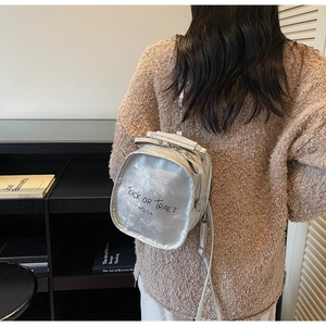 Detail of silver metallic mini backpack with letter print on a knit sweater background