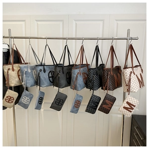 Detail view of large letter print tote bags with matching small pouches on metal rack