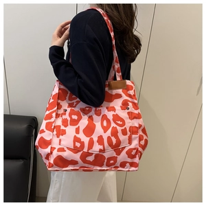 Détail du sac cabas en nylon imprimé léopard rouge avec poche avant et rivets métal