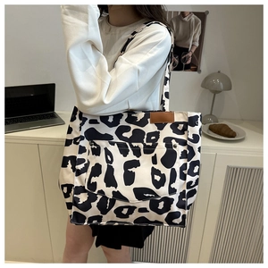 Detail of the large canvas tote bag showing the leopard print pattern and front pocket