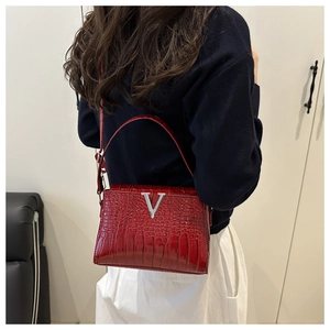 Detail of red crocodile textured leather handbag with silver V-shaped metal buckle