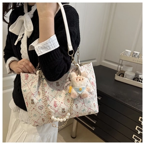 Détail du sac cabas floral avec imprimé ours, breloque en peluche et chaîne en perles
