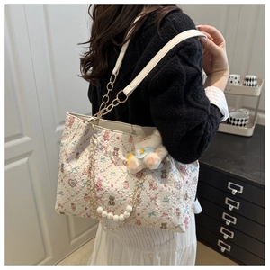 Détail du sac cabas floral avec chaîne de perles et pendentif animal en peluche