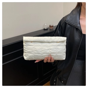 Detail of white quilted envelope clutch featuring grid stitching and metal fastener