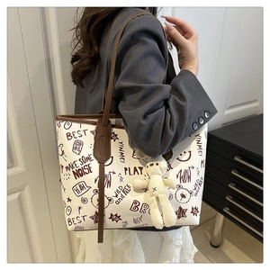 Detail of printed large capacity tote bag with graffiti patterns and bear charm