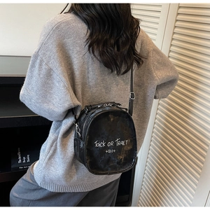 Detail of retro black round crossbody bag with white graffiti text and dual zippers