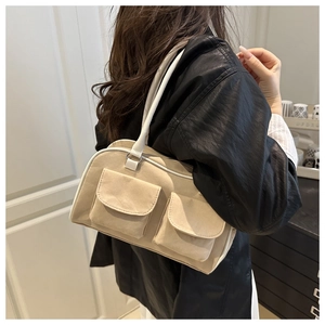 Detail of beige vintage suede shoulder bag showing dual front flap pockets and strap rings