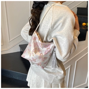 Close-up of pink satin bucket bag with detailed butterfly embroidery and silk tassel