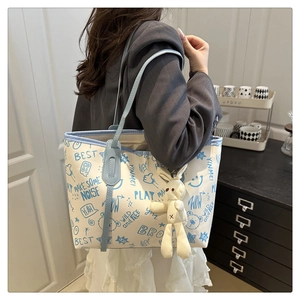 Détail du sac cabas blanc cassé avec imprimés graffiti bleus et charm lapin mignon