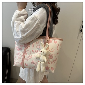 Detail of white printed tote bag with pink graffiti patterns and a cute rabbit pendant