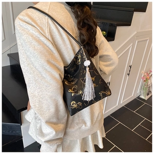 Detail of black bucket bag featuring golden butterfly embroidery and lotus tassel