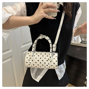 Detailed view of polka dot cylindrical handbag with double handles and shoulder strap