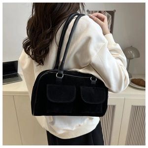 Detail view of black suede shoulder bag with dual front pockets and silver ring accents
