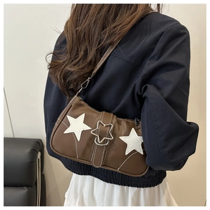 Detailed view of a brown pebbled leather shoulder bag with white star appliques and metal buckle