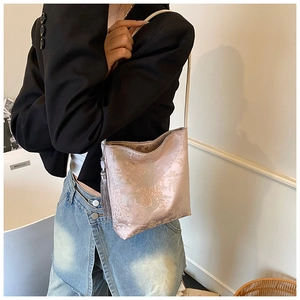 Detail of pink floral embroidery texture and grey fringe on a stylish bucket bag