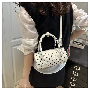 Polka dot cylinder bag with adjustable strap shown from a back-view model perspective