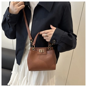 Detail showing brown lychee textured leather bag with gold metal twist lock and handle