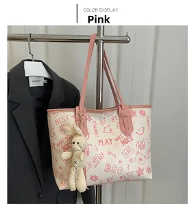 Close-up of stylish white tote bag with pink graffiti prints and cute rabbit pendant