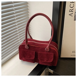 Deep red suede handbag detail featuring double front pockets and elegant curved handle