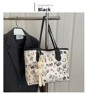 Close-up of a black and white graffiti tote bag featuring a cute white bunny plush charm