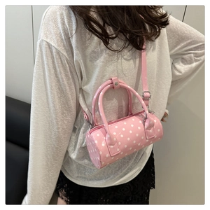 Detailed view of a pink polka dot cylinder crossbody bag worn by a model