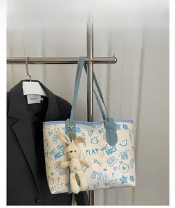 Detail of blue graffiti tote bag featuring bunny charm and artsy cartoon prints