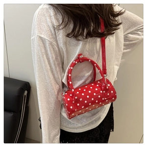 Detailed side view of the red polka dot barrel bag worn by a model in a casual setting