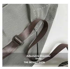 Detail of adjustable dark brown strap on grey textured tote bag with contrast stitching