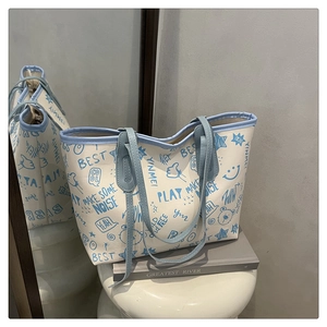 Detail of printed tote bag showing blue graffiti pattern and sleek leather handle