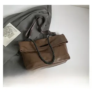 Macro detail of brown soft PU tote bag with woven rope handle and adjustable strap