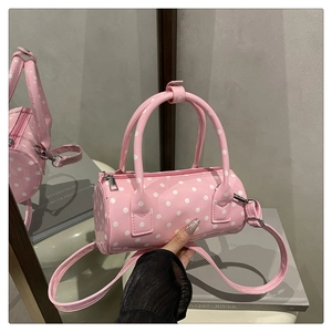 Close-up of pink polka dot barrel bag with glossy finish and polished metallic hardware