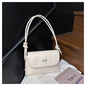 Détail du sac bandoulière crème avec nœud noir chic et bandoulière à cordon noué