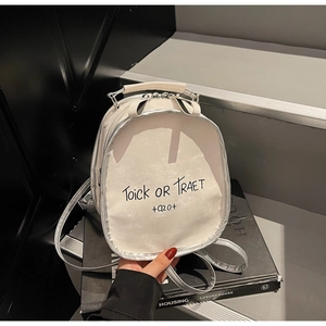 Detail of silver mini backpack with bow handle and metallic finish on dark steps