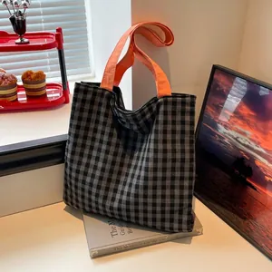 Checkered canvas tote bag with orange handles shown in a cozy home setting decor