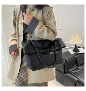 Detail of black PU leather tote bag with thick rope handle and wide strap on a model