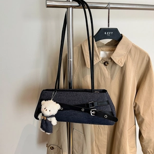Detail of blue denim bag with black PU straps and cute teddy bear charm accessory