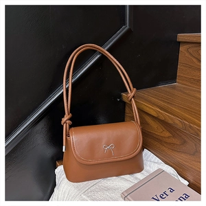 Détail d'un sac bandoulière en cuir marron avec nœud métallique et sangle nouée