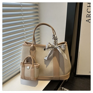 Detail of khaki canvas handbag with brown leather trim, mini charm and decorative silk scarf
