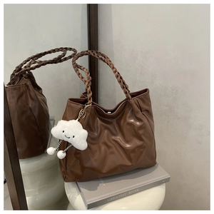 Detailed texture of brown embossed tote bag with braided handles and cloud charm