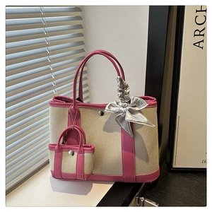 Close-up of canvas tote bag with pink leather trim, mini pouch, and decorative silk scarf