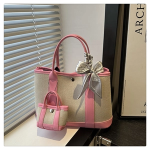 Detail view of canvas tote with pink leather trim, silk scarf handle, and mini pouch