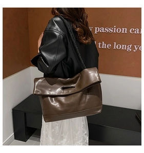 Detail of a large dark brown PU leather tote bag with stylish braided chain strap