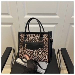 Close-up of leopard print tote bag with black handles and metal zipper pocket detail
