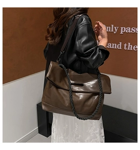 Detail of dark brown PU tote bag featuring a textured spiral woven shoulder strap style
