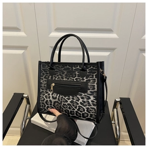 Close-up of leopard print tote bag with black leather trim and front metal zipper pocket